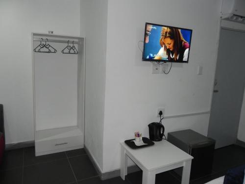 a room with a tv on a wall with a table at De Bliss Lodge in Johannesburg