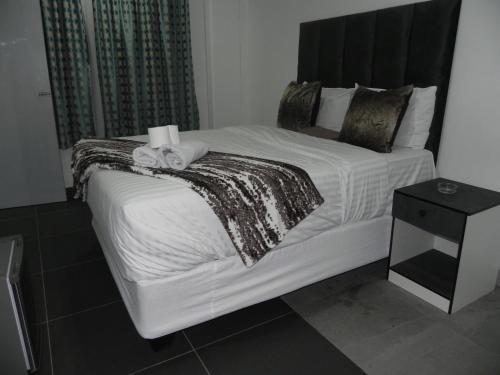 a bedroom with a large white bed with towels on it at De Bliss Lodge in Johannesburg