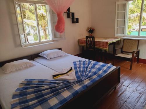 a bedroom with a bed and a table and windows at Piyanivasa in Ambalangoda