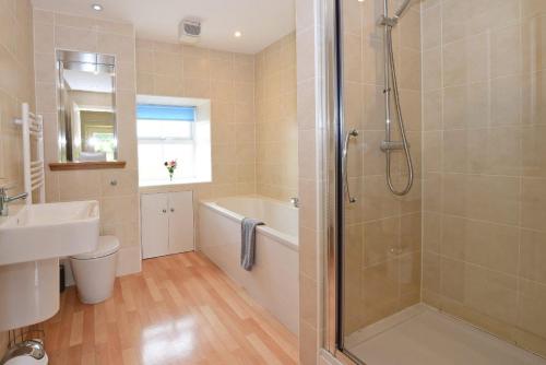 a bathroom with a shower and a toilet and a sink at Hawthorn House in Pathhead