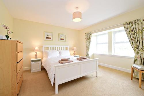 a bedroom with a white bed and a window at Hawthorn House in Pathhead