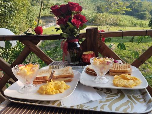 two plates of breakfast food on a table with roses at Casa del árbol Mirador Peñero in La Peña
