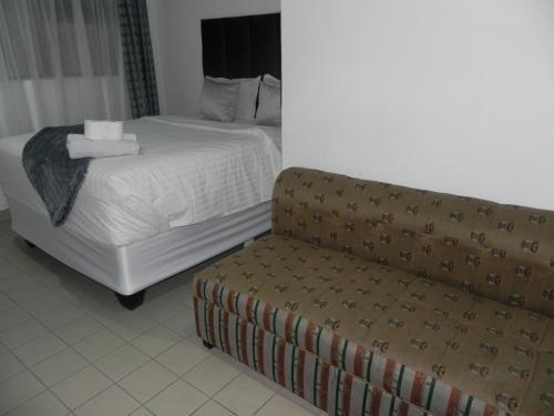 a hotel room with a bed and a couch at De Bliss Lodge in Johannesburg