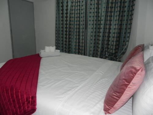 a bed with red and white sheets and pillows at De Bliss Lodge in Johannesburg