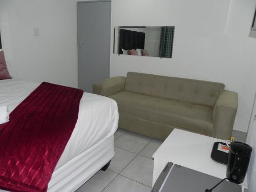 a bedroom with a bed and a couch in a room at De Bliss Lodge in Johannesburg