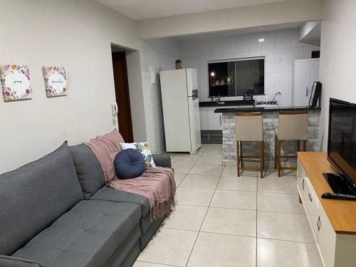 a living room with a couch and a kitchen at Apto Araguari c/ Piscina in Araguari