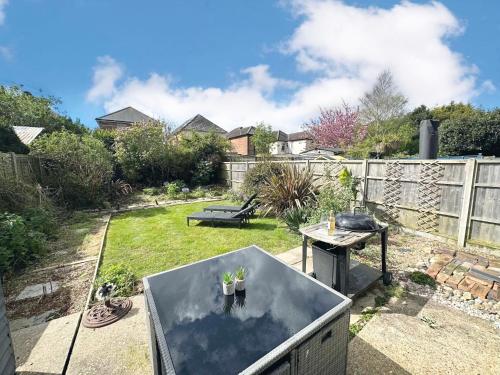 a small backyard with a table and a grill at The Capstone Retreat - Beautiful Detached Family Home By Coastline Retreats, Arcade Machine, Parking, BBQ in Bournemouth