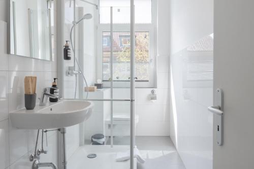 y baño blanco con lavabo y ducha. en Modernes Apartment in top Lage komfortabel eingerichtet mit Arbeitsplatz und Küche - Geibelsuite, en Hannover