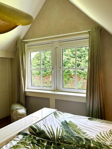 a bedroom with two windows and a bed in a room at Golden Wellness Villa Noordwijk in Noordwijk