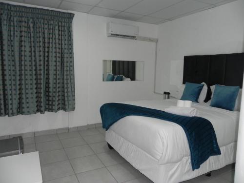 a bedroom with a large bed with blue pillows at De Bliss Lodge in Johannesburg