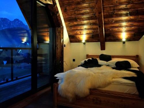 a bedroom with a large white bed with a window at Domki TATRA HOMES z jacuzzi in Kościelisko