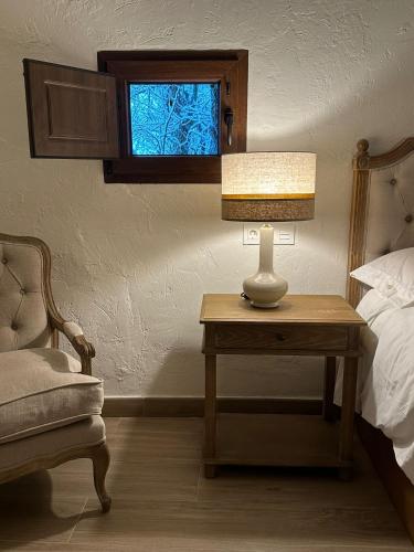 a bedroom with a bed and a table with a lamp at HOTEL RURAL SANTUI in Horcajuelo de la Sierra