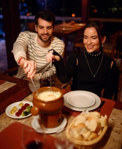 a man and a woman sitting at a table with a drink at Hotel Fazenda Monte Castelo in Gravatá
