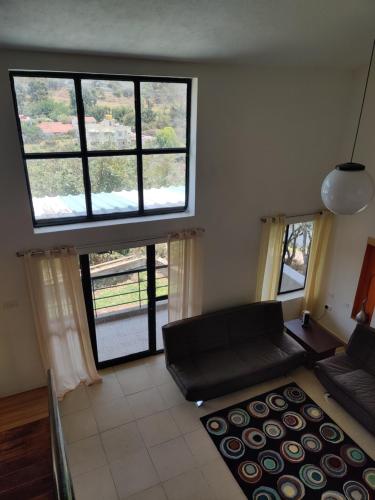 a living room with a couch and two large windows at Haven Guest House in Kodaikānāl