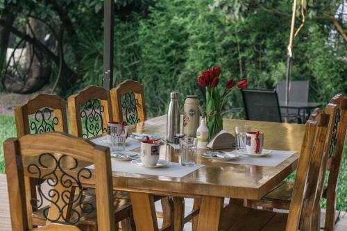 a wooden table with chairs and a table with red flowers at Quinta La Paloma in Itauguá