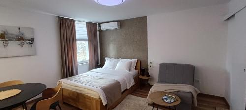 a bedroom with a bed and a table and a window at Studio apartman Peti in Varaždin