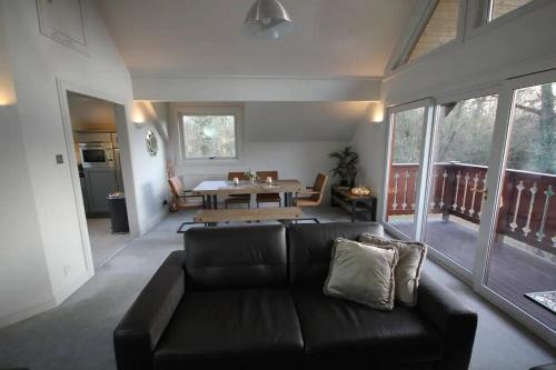 - un salon avec un canapé noir et une table dans l'établissement Private Estate Lake Lodge-Cabin Near River Thames, à Buckinghamshire