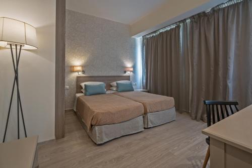 a bedroom with a bed with two blue pillows at Lefkoniko Beach & Icarus Suite Apts in Rethymno Town