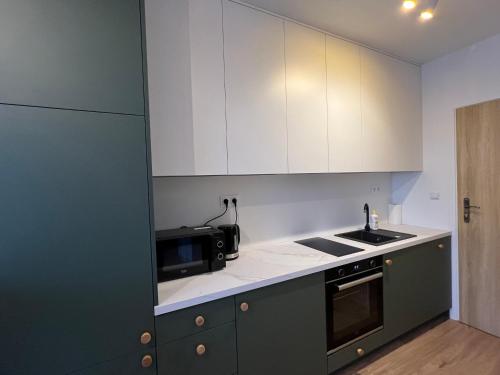 ヴロツワフにあるI&M Apartments Stawowa Wrocławの白いキャビネット、シンク、電子レンジ付きのキッチンが備わります。