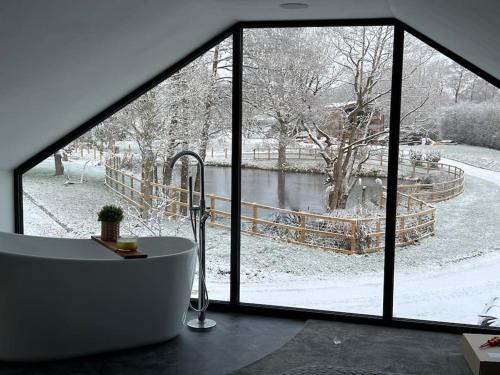 uma casa de banho com uma banheira em frente a uma janela em Waters Edge, Eaton em Congleton