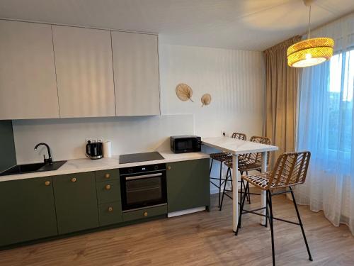 una cocina con armarios verdes, mesa y sillas en I&M Apartments Stawowa Wrocław en Wroclaw