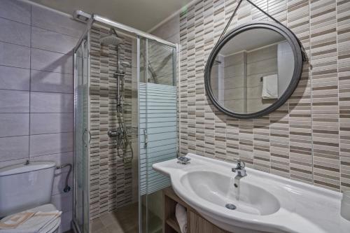 a bathroom with a sink and a mirror and a toilet at Lefkoniko Beach & Icarus Suite Apts in Rethymno