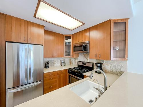 a kitchen with wooden cabinets and a stainless steel refrigerator at *WEHO/Beverly Hills* Luxury 2BD/2.5BA + Balconies in Los Angeles