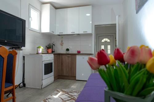 a kitchen with a table with flowers in a vase at Vila apartment Astorija 2 in Podgorica