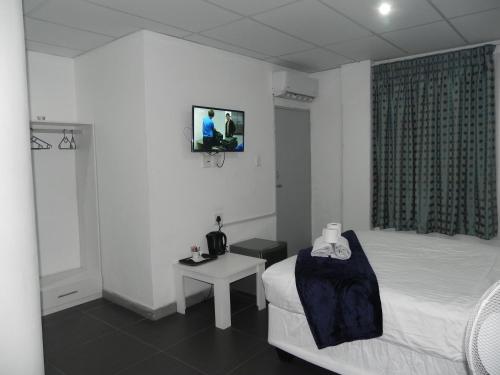 a bedroom with a bed and a tv on the wall at De Bliss Lodge in Johannesburg
