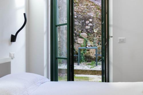 a bedroom with a window looking out at a yard at Cà del Lasco - Free parking apartments 5 min from the station in Bellano