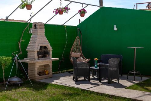 a patio with a fireplace and chairs and a green wall at Vila apartment Astorija 2 in Podgorica