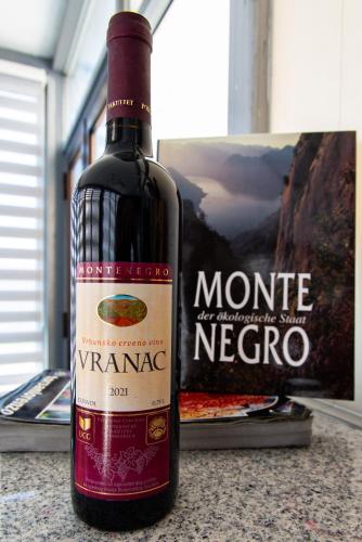 a bottle of wine sitting on a counter next to a book at Vila apartment Astorija 2 in Podgorica