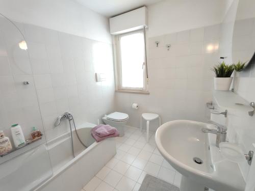 a white bathroom with a tub and a sink at Nice apartments lake view & free parking in Pastrengo