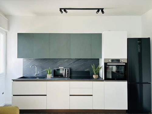 uma cozinha com armários brancos e um frigorífico preto em Ca' D'Amore em Treviso