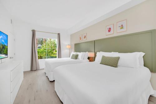 two white beds in a white room with a window at Boho Oasis 1 mile Disney Springs in Orlando