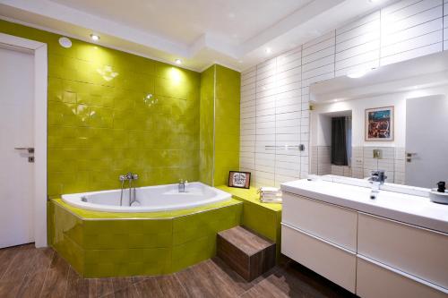 een groene badkamer met 2 wastafels en een bad bij Our Happy Place Maisonette in Kavala