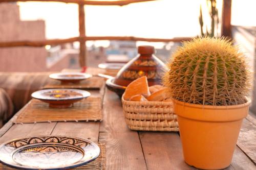 een houten tafel met borden en een cactus erop bij ntonasurfhouse in Imsouane