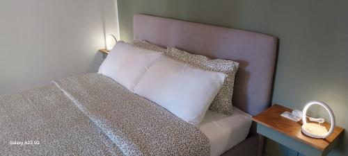 ein Bett mit weißen Kissen und einem hölzernen Nachttisch in der Unterkunft Little Sweet Home - Fiera Milano in Pero