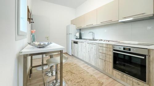 een keuken met witte kasten, een tafel en een wastafel bij Bright & Spacious Apartment near city center. in Thessaloniki