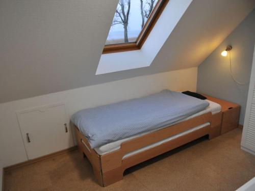 a small bedroom with a bed with a window at Holiday home Crane Coast in Kinnbackenhagen