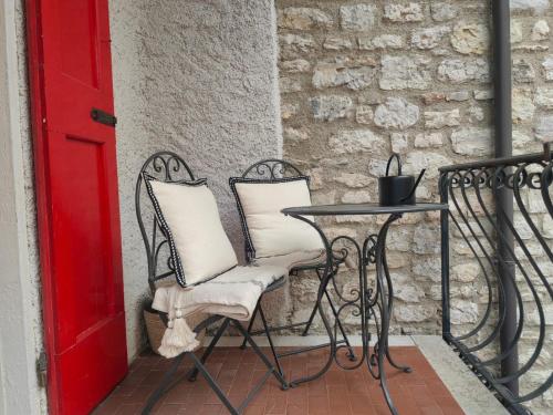 a table and chairs on a balcony with a red door at Casa Storica Gardola in Tignale