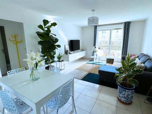 a living room with a white table and some plants at L'écrin du stade By UTA HOUSE in Saint-Denis