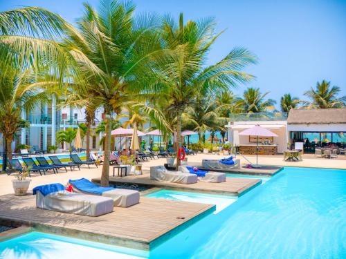 a pool with chaise lounge chairs and palm trees at Tamala Beach Resort in Kotu