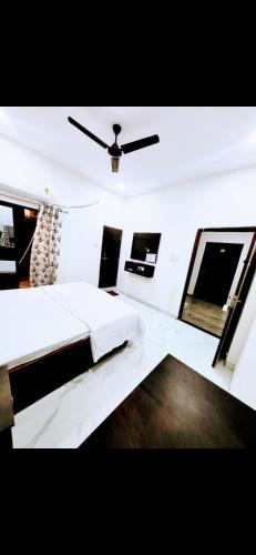 1 dormitorio con cama blanca y ventilador de techo en Paradise Inn, en Indore