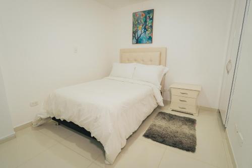 a white bedroom with a bed and a night stand at Exclusivo Apartaestudio en Pinares- 5 in Pereira