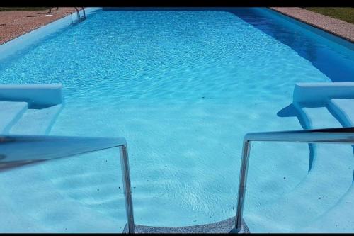 a blue swimming pool with two chairs in it at Casa do Vale - Moradia 3 quartos - Rio Minho-Seixas-Caminha - Casa de férias completa com piscina in Caminha