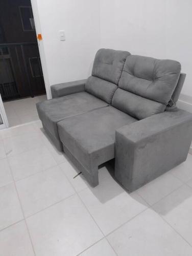 un sofá gris sentado en una sala de estar en Quarto privativo, en Florianópolis