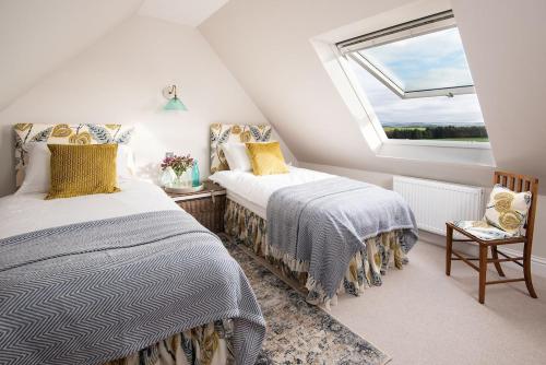 una camera mansardata con due letti e una finestra di Greenhead Cottage a Kelso