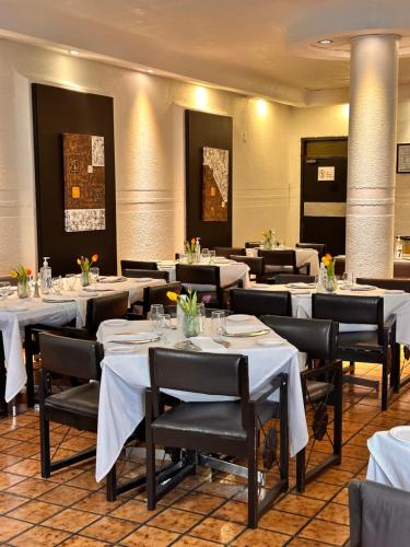 une salle à manger avec des tables blanches et des chaises noires dans l'établissement Hotel del Fresno, à Fresnillo de González Echeverría