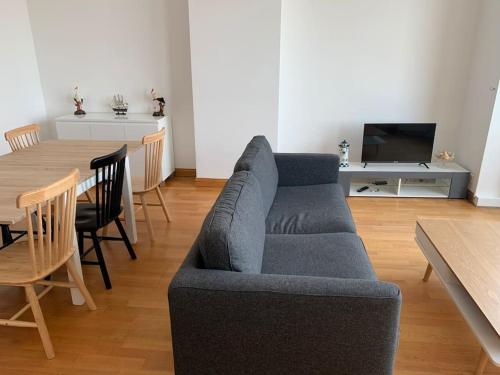 uma sala de estar com um sofá azul e uma mesa em l'Éclat du Littoral Vue mer - Good Home em Dunkerque